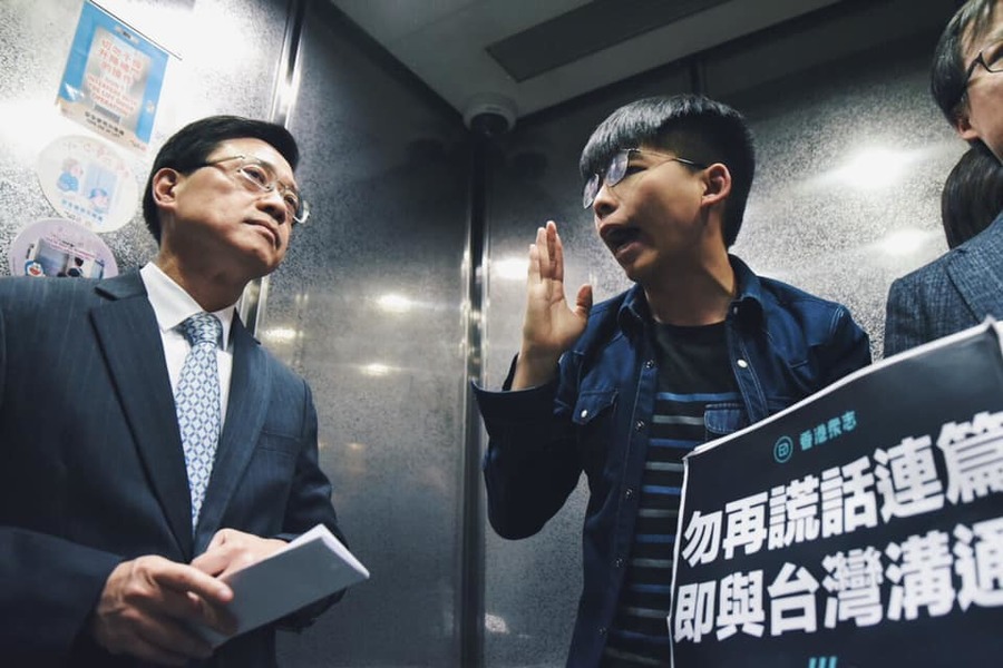 李家超13日向媒體說明修法時,香港眾志黃之鋒等人也到場示威,要求撤回修法並跟台方商討,他後來更擠入李家超乘搭的電梯內繼續抗議。(photo by 香港眾志)