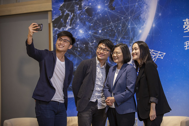 蔡英文與第1屆完成海外實習的3位記者在台上進行自拍。(總統府提供)