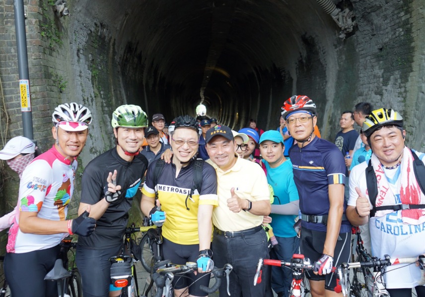 新北市長侯友宜(中)13日上午視察7日通車的汐止基隆自行車道,於台鐵五堵貨場舊隧道前與車友合照。(photo by新北市高管處)